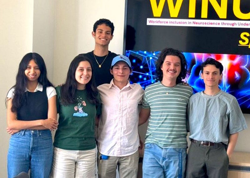 Five people standing arm in arm smiling