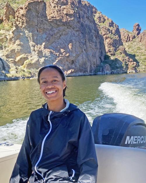 A woman in a black jacket sits on a boat on Saguaro lake.