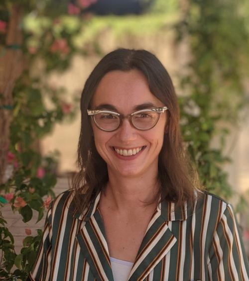 A woman with brown hair and glasses smiles at the camera.