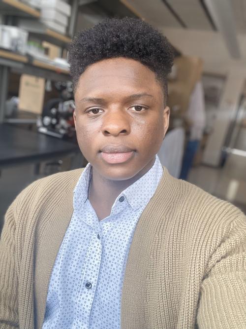 Headshot of Addison Smith wearing a blue and white button down shirt and beige sweater