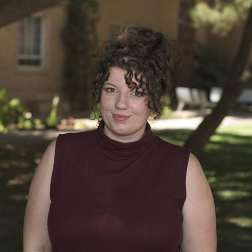 A smiling woman with brown hair and a red shirt.