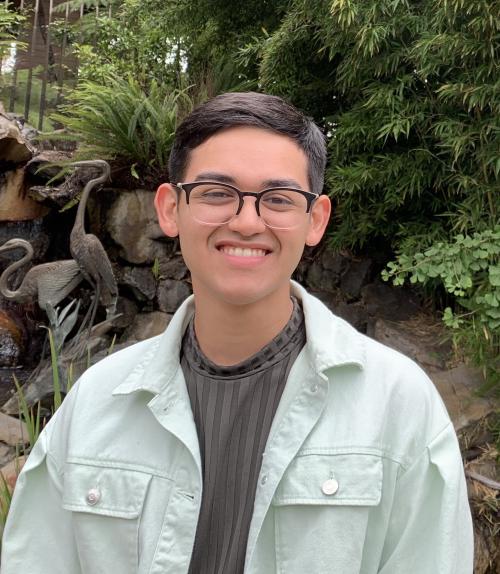 A smiling man with glasses, standing in front of two herons.