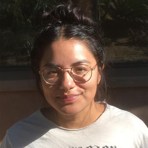 A woman with glasses and black hair smiling at the camera.