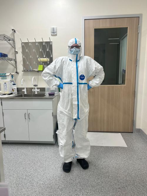 A person clad in a protective white lab suit, standing proudly with their hands on their hips.