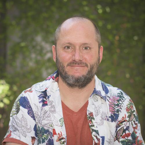 Headshot of Krijn Paaijmans wearing a red shirt underneath a blue, white, black, and red Hawaiian print button down