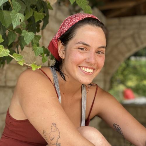 headshot of Risa Schnebly wearing a red bandana on her head, smiling, and wearing a red tank top