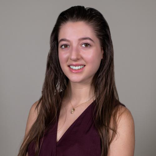 A woman smiling in front of a gray background